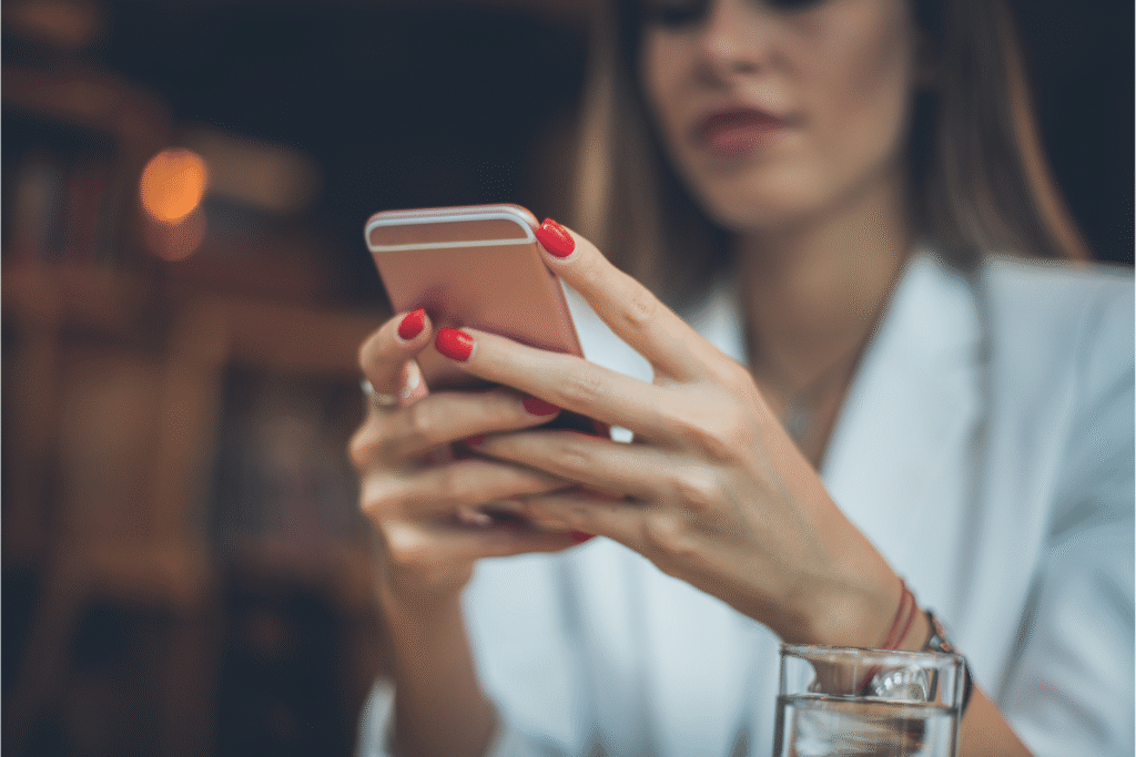 Call Forwarding to Personal Cell Phone - This is a picture of a well dressed woman with red fingernails holding a cell phone in her hand and appears to be reading something on the phone screen.