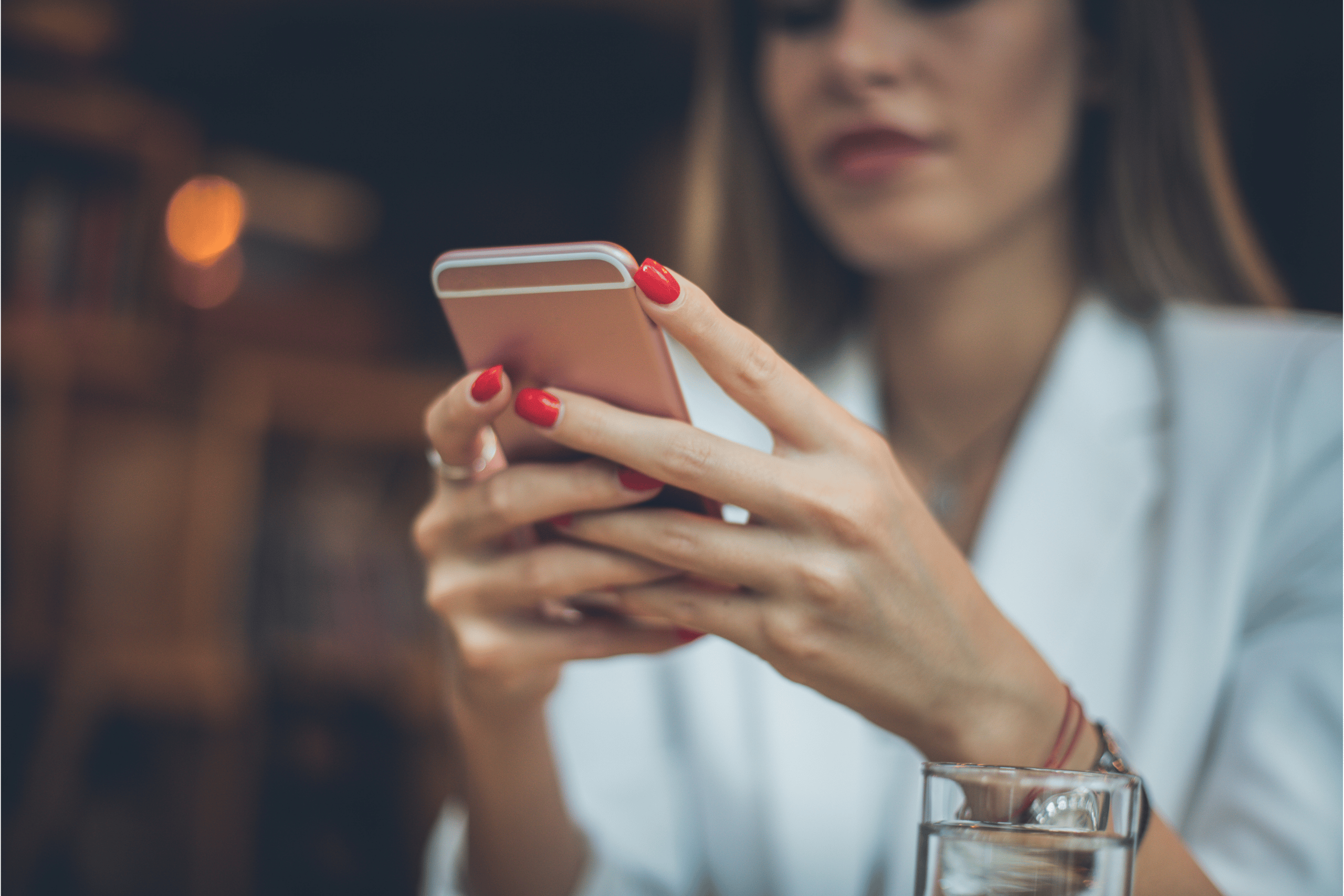 Call Forwarding to Personal Cell Phone - This is a picture of a well dressed woman with red fingernails holding a cell phone in her hand and appears to be reading something on the phone screen.