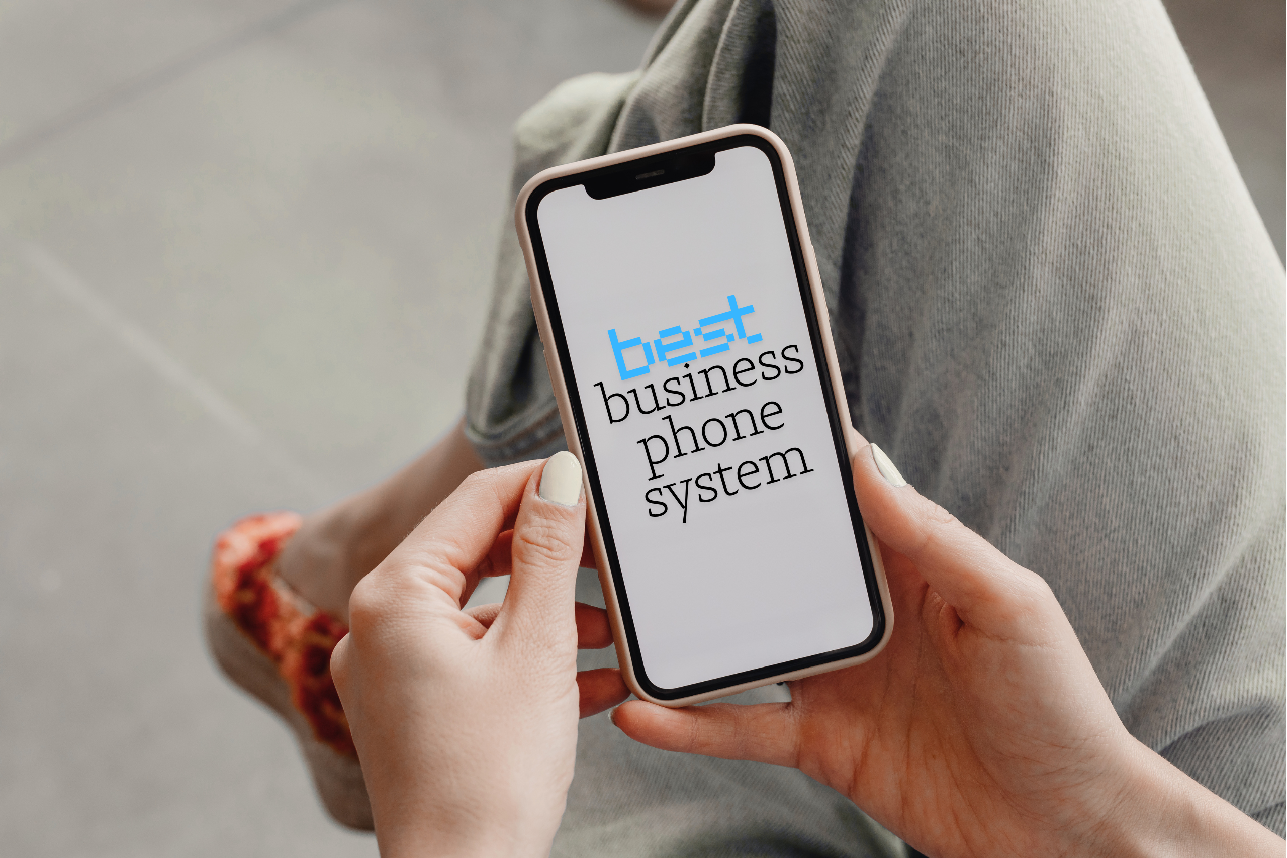 Photo showing the cell phone screen of a white woman sitting with leg crossed. The screen says Best business phone system.
